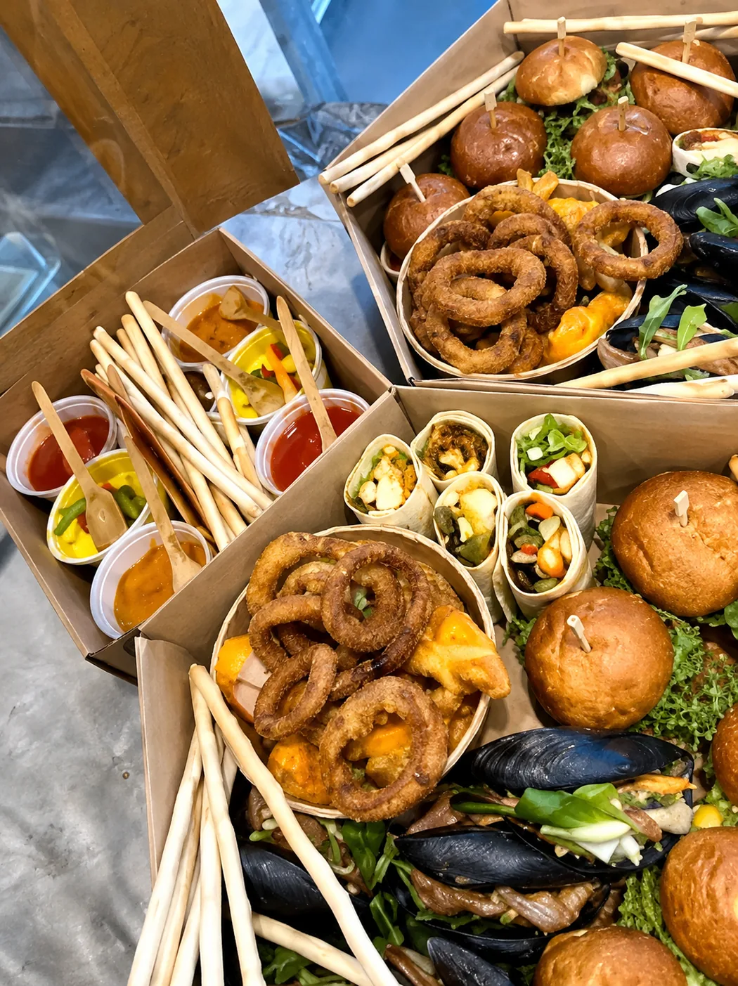 Zestawy PartyBox w kartonach — burgery, wrapy, krążki cebulowe i sosy w osobnych porcjach
